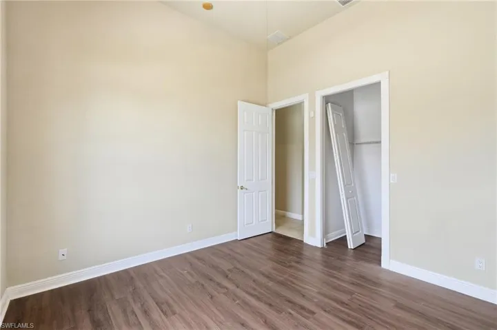 Spacious room featuring wood-finish flooring, light neutral wall paint, and white baseboards