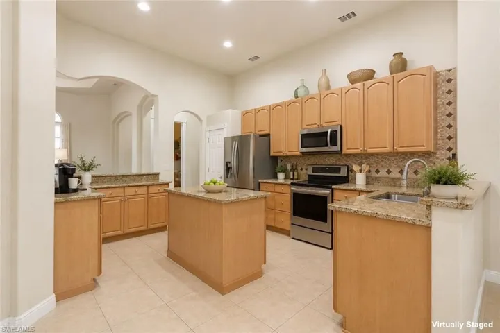 Spacious kitchen featuring light wood cabinetry, granite countertops, a central island, recessed lighting, and stainless steel appliances
