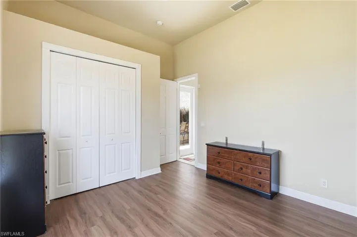 Room featuring wood-finish flooring, vaulted ceilings, and white bi-fold closet doors