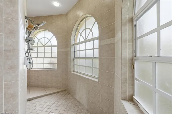 Walk-in shower with full tile surround, integrated shower bench, and multiple arched windows with frosted glass