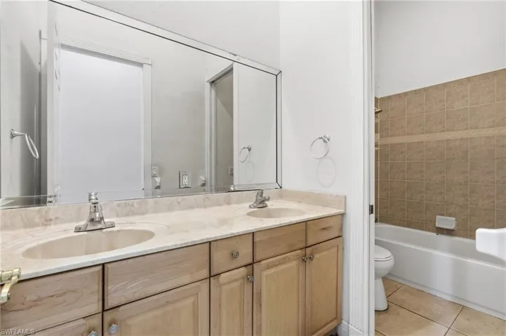 Double vanity featuring a light-toned countertop with integrated sinks and wood cabinetry