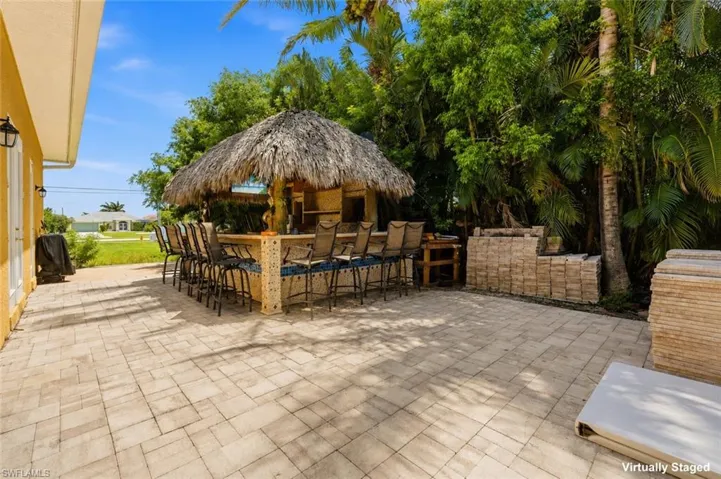 Expansive paver patio featuring a built-in tiki bar with a thatched roof