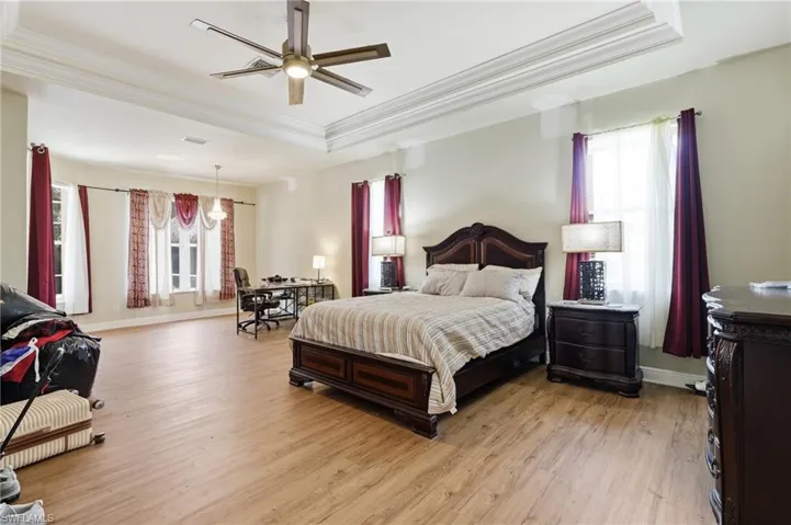 Spacious room with wood-finish flooring and a multi-tiered tray ceiling