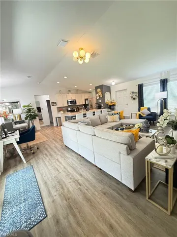Living room with vaulted ceiling, light wood-style floors, recessed lighting, and a chandelier