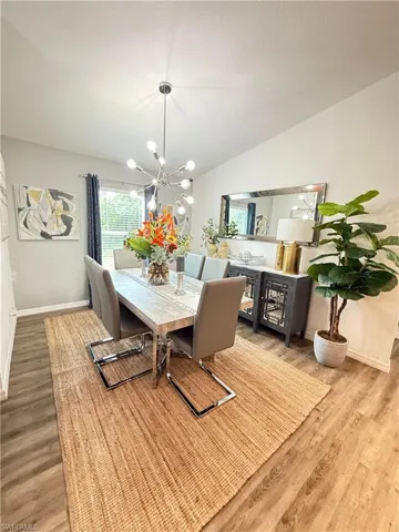 Dining area featuring light wood-type flooring, a chandelier, and vaulted ceiling