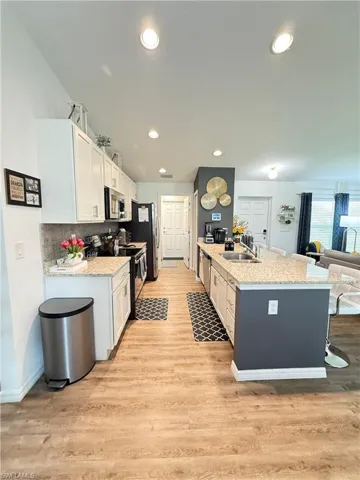 Kitchen featuring stainless steel appliances, white cabinets, light wood finished floors, recessed lighting, and tasteful backsplash