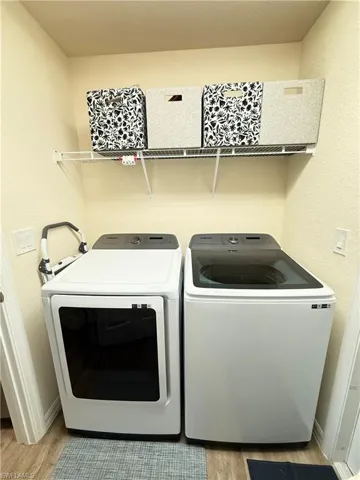 Laundry room with wood finished floors and independent washer and dryer