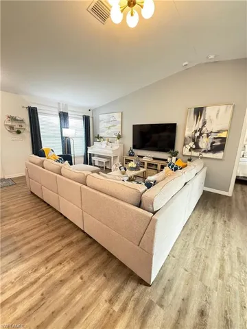 Living area with wood finished floors, lofted ceiling, and a chandelier