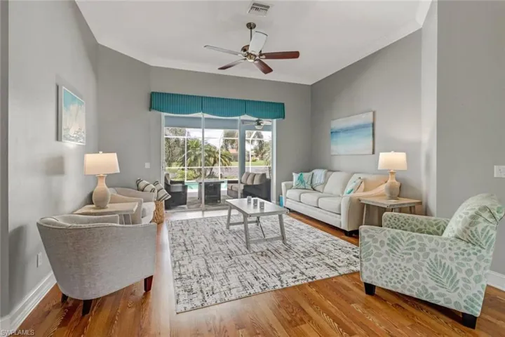 Living room with a ceiling fan, wood finished floors, crown molding, and a sunroom