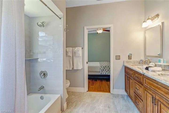 Ensuite bathroom with double vanity, shower / bath combo with shower curtain, and ceiling fan