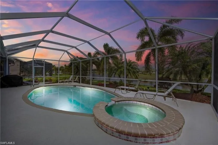 Combined pool / hot tub with a sunroom, a lanai, area for grilling, and a patio area
