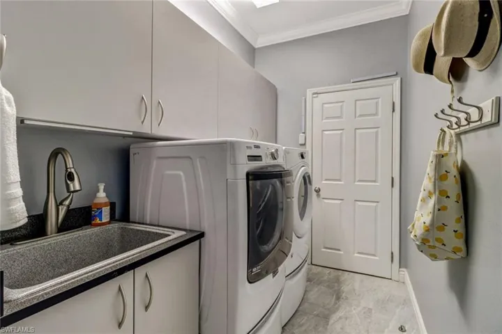 Laundry room featuring ornamental molding, cabinet space, and separate washer and dryer
