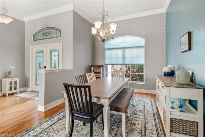Dining area with ornamental molding, light wood-style flooring, healthy amount of natural light, hanging lights, and french doors
