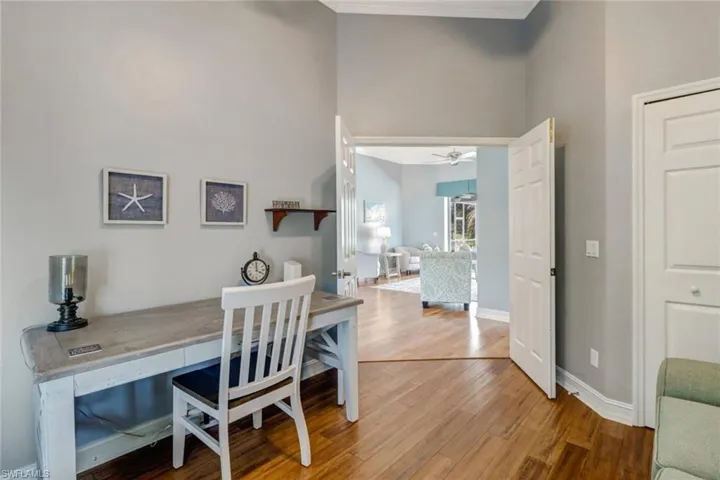 Office space featuring light wood-type flooring, crown molding, a ceiling fan, and a high ceiling