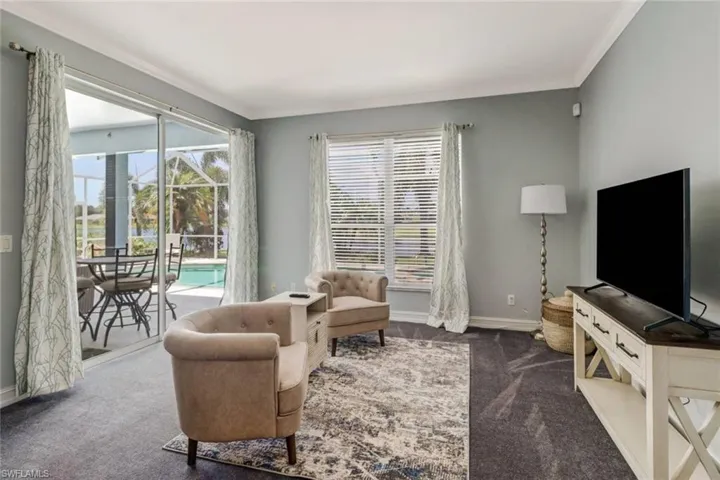 Living area with dark carpet, crown molding, and a sunroom