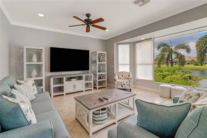 Tiled living area featuring a ceiling fan, recessed lighting, and crown molding