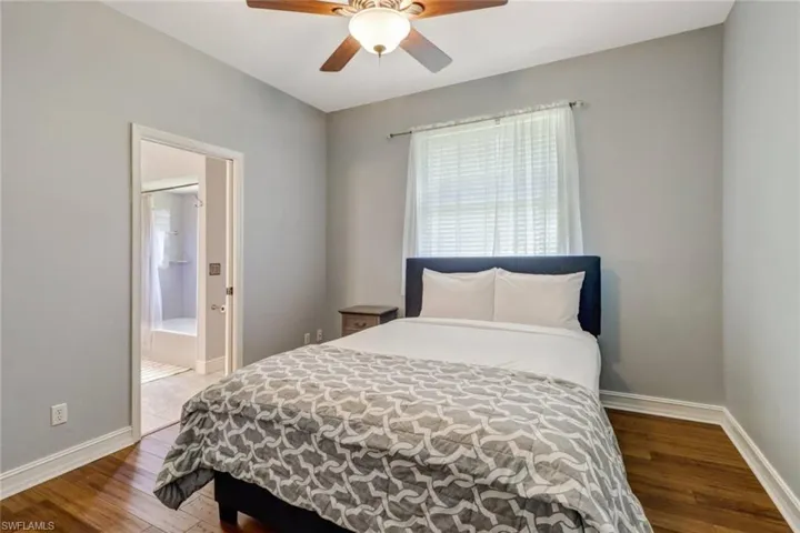 Bedroom with hardwood / wood-style floors, ceiling fan, and connected bathroom