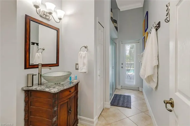 Full bathroom featuring a stall shower, vanity, a high ceiling, light tile patterned floors, and ornamental molding