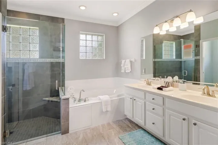Bathroom with a stall shower, double vanity, a garden tub, and crown molding