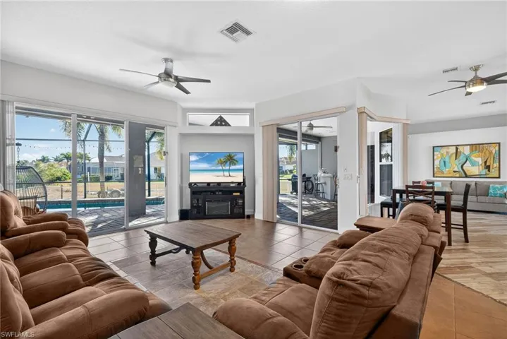 Living room featuring ceiling fan, a fireplace, and light tile patterned floors