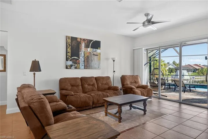 Tiled living area featuring a ceiling fan and a sunroom