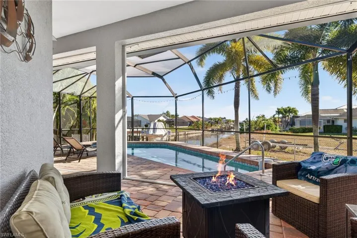 Swimming pool featuring an outdoor living space with a fire pit, a patio, glass enclosure, a sunroom, and a residential view