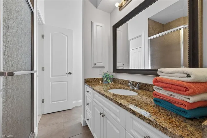 Bathroom with a stall shower, vanity, and light tile patterned flooring