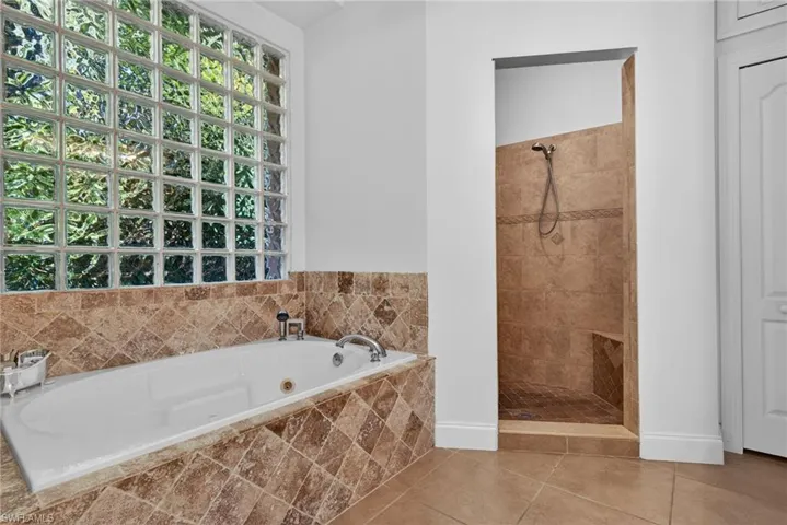 Bathroom with tiled shower, a whirlpool tub, and tile patterned flooring