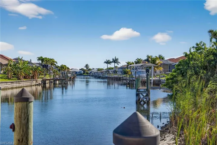 Water view featuring a boat dock, nearby suburban area, and boat lift