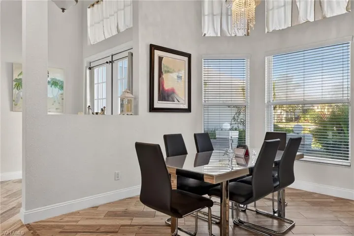 Dining area featuring light wood-style floors, a chandelier, and a towering ceiling