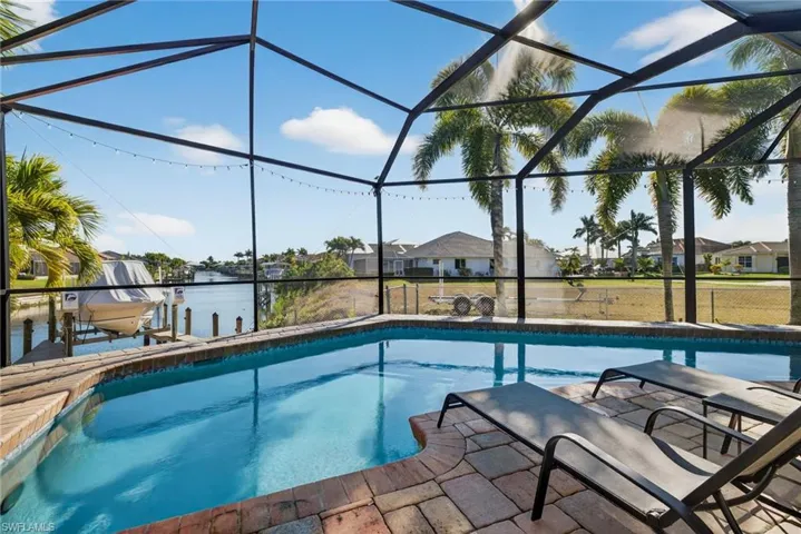 Swimming pool with boat lift, glass enclosure, a sunroom, a residential view, and a boat dock