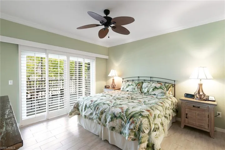 Bedroom with ornamental molding, access to exterior, wood finished floors, a ceiling fan, and baseboards