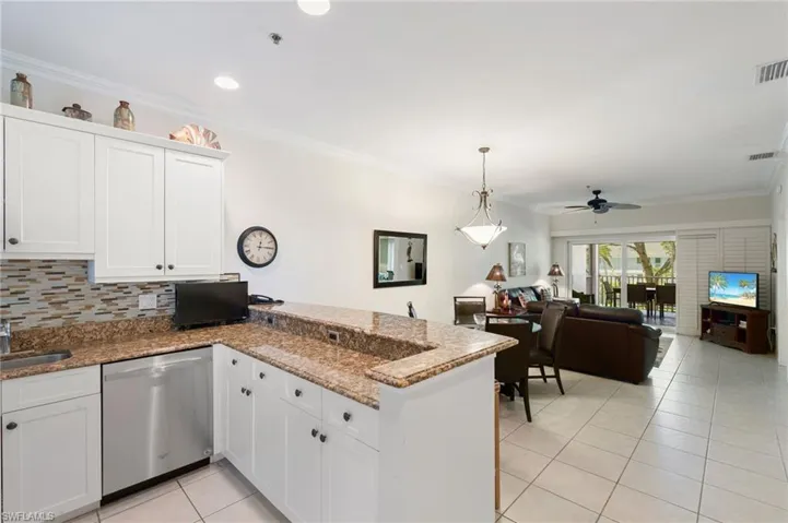 Kitchen with stainless steel dishwasher, a peninsula, light tile patterned floors, ceiling fan, and white cabinetry