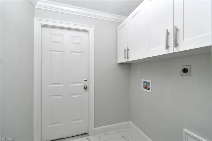 Laundry area featuring baseboards, marble finish floor, cabinet space, electric dryer hookup, and washer hookup
