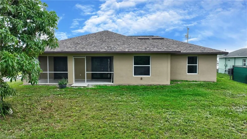 Back of house featuring a shingled roof, a lawn, stucco siding, and a sunroom