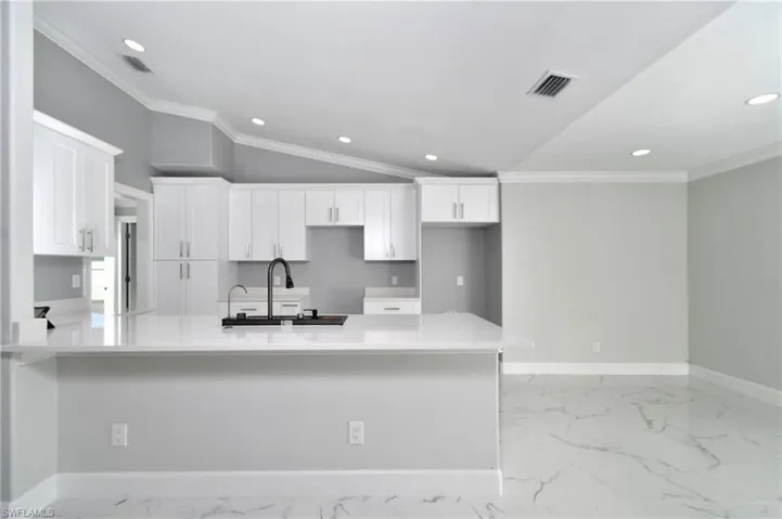 Kitchen featuring baseboards, visible vents, a sink, and white cabinetry