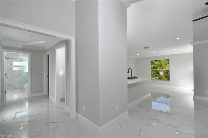 Hall featuring marble finish floor, baseboards, recessed lighting, and ornamental molding