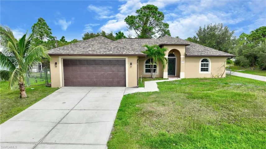 View of front of home featuring a front yard, stucco siding, fence, and concrete driveway