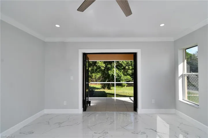 Spare room with marble finish floor, a ceiling fan, ornamental molding, and baseboards