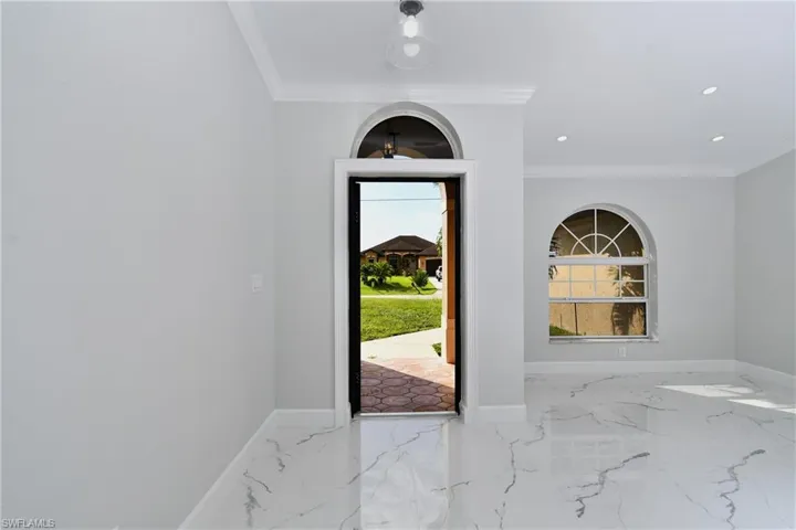 Entryway featuring marble finish floor, baseboards, and crown molding