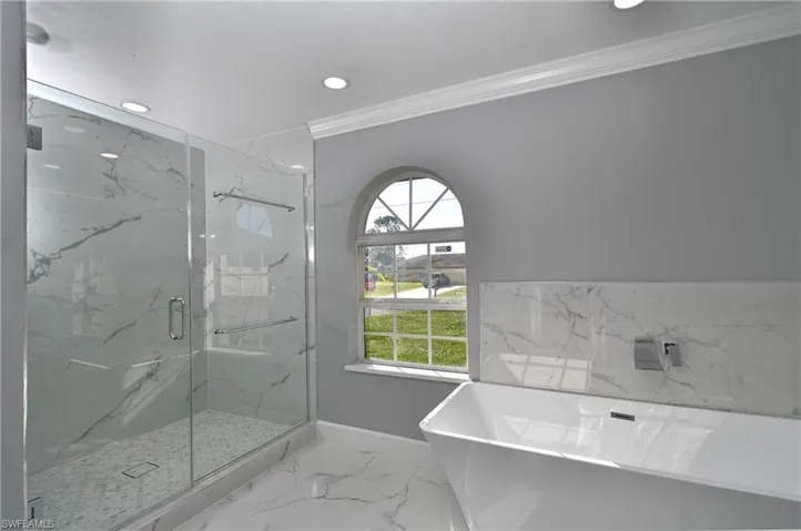 Full bath with marble finish floor, ornamental molding, a marble finish shower, recessed lighting, and a freestanding bath