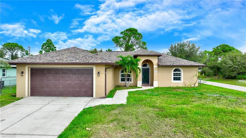 Ranch-style home with stucco siding, driveway, and a front yard