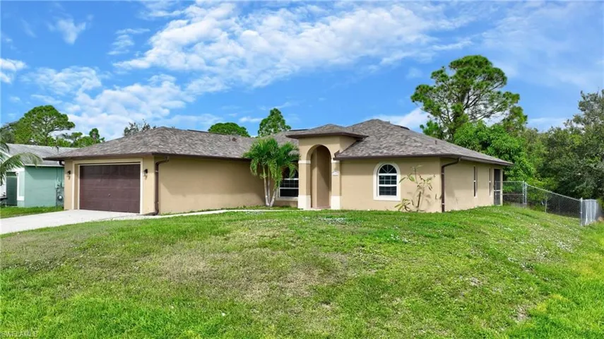View of front of home with fence, driveway, stucco siding, and a garage