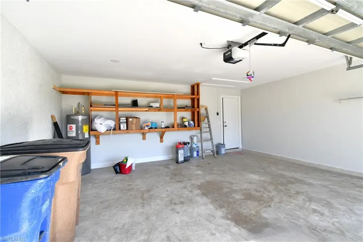 Garage featuring water heater, baseboards, and a garage door opener