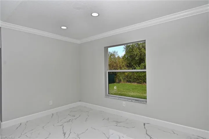 Empty room featuring crown molding, recessed lighting, baseboards, a textured ceiling, and marble finish floor