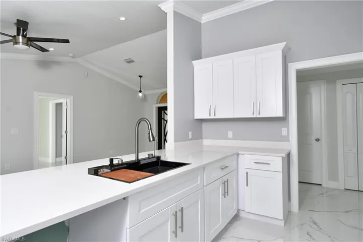 Kitchen with visible vents, crown molding, marble finish floor, ceiling fan, and a sink