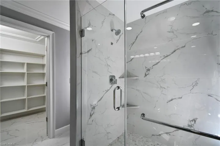 Bathroom featuring marble finish floor, crown molding, and a marble finish shower