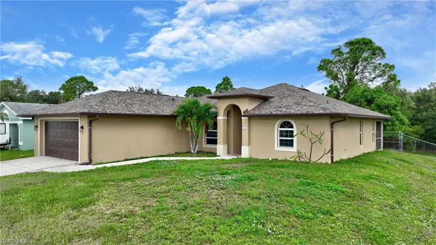 View of front of property with stucco siding, driveway, a garage, and a front lawn