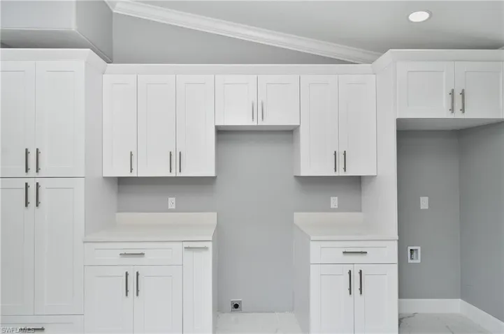 Kitchen featuring marble finish floor, light countertops, and ornamental molding