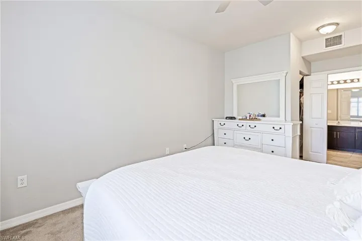 Carpeted bedroom with ceiling fan and connected bathroom